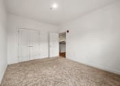 Thumbnail 25 of 25 - A room with white walls and a carpeted floor with a door and a closet.