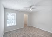 Thumbnail 8 of 23 - A room with a ceiling fan and carpeted floor.