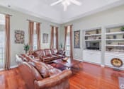 Thumbnail 16 of 23 - A living room with a brown leather couch and a fan on the ceiling.