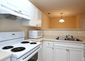 Thumbnail 1 of 23 - A white stove and oven in a kitchen with white cabinets.