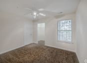 Thumbnail 7 of 23 - A room with a ceiling fan and carpeted floor.