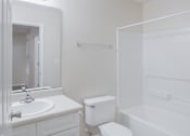 Thumbnail 9 of 23 - A white bathroom with a toilet, sink, and bathtub.
