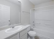 Thumbnail 10 of 23 - A white bathroom with a toilet, sink, and bathtub.