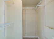 Thumbnail 6 of 16 - A walk-in closet with white shelving and hanging rods.
