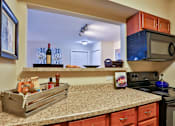 Thumbnail 17 of 17 - A kitchen with a black stove and a black microwave above it at The Bristol Apartments, South Carolina