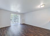 Thumbnail 5 of 10 - an empty living room with wood flooring and a sliding glass door at Carolina Springs Apartments, Carrboro, North Carolina  
