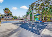 Thumbnail 16 of 19 - A playground with a blue umbrella and a basketball court.