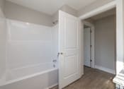 Thumbnail 9 of 23 - A white bathroom with a tub and a door at Dunean Creek Apartments, Greenville, South Carolina