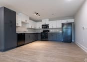 Thumbnail 2 of 23 - A kitchen with black cabinets and a wooden floor at Dunean Creek Apartments, Greenville