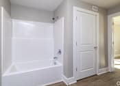 Thumbnail 15 of 23 - A white bathroom with a tub and a door at Dunean Creek Apartments, Greenville, 29611