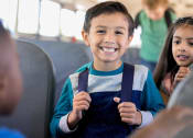 Thumbnail 7 of 16 - a young boy and girl sitting on a bus holding their school bags