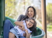 Thumbnail 11 of 16 - a mother and daughter laughing on a playground slide