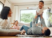 Thumbnail 4 of 16 - a family playing in their living room with a child on their