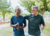 Thumbnail 10 of 16 - two men walking in the park holding bottles of water