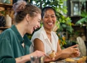 Thumbnail 14 of 16 - two women sitting at a table eating food