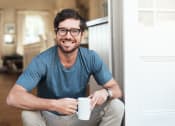 Thumbnail 15 of 16 - a man sitting on a door holding a coffee cup