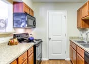 Thumbnail 16 of 17 - a kitchen with wood cabinets and granite countertops at The Bristol Apartments, Greenville, SC, 29601