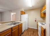 Thumbnail 3 of 11 - A kitchen with wooden cabinets and a white refrigerator at Lakeside Gardens Apartments, North Carolina