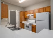 Thumbnail 2 of 26 - a kitchen with white appliances and wooden cabinets at Magnolia Lake Apartments, Georgia