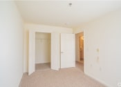 Thumbnail 16 of 28 - a bedroom with white doors and carpeting and a hallway to a closet