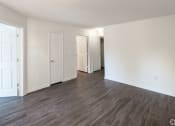 Thumbnail 10 of 21 - an empty living room with white walls and wood flooring at Pendleton Townhomes Apartments, North Carolina