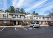 Thumbnail 4 of 21 - an apartment building with a parking lot and cars in front of it at Pendleton Townhomes Apartments, Durham, 27703