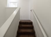 Thumbnail 19 of 21 - a stairwell with carpeted stairs leading up to a window at Pendleton Townhomes Apartments, Durham, NC