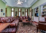 Thumbnail 7 of 15 - a living room with leather furniture and a ceiling fan