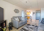 Thumbnail 1 of 13 - A living room with a grey couch and a television.