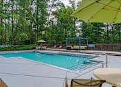 Thumbnail 15 of 17 - A pool surrounded by trees and a yellow umbrella.