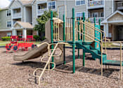 Thumbnail 19 of 26 - A playground with a green slide and a red slide.