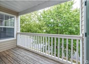 Thumbnail 14 of 26 - A balcony with a white railing and a window overlooking a green tree.