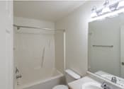 Thumbnail 12 of 26 - A white bathroom with a toilet, sink, and bathtub.