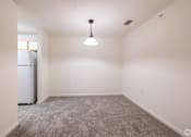Thumbnail 6 of 26 - A room with a grey carpet and a white fridge.
