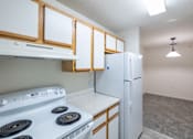 Thumbnail 5 of 26 - A kitchen with a white stove top oven and a white refrigerator.