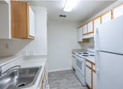 Thumbnail 4 of 26 - A kitchen with white appliances and wooden cabinets.