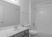 Thumbnail 10 of 17 - A white bathroom with a marble countertop and a toilet.