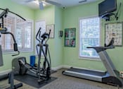 Thumbnail 17 of 17 - A home gym with a treadmill, elliptical trainer, and stationary bike.