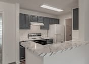 Thumbnail 9 of 17 - A kitchen with a marble countertop and dark grey cabinets.
