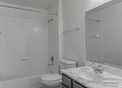 Thumbnail 14 of 17 - A white bathroom with a toilet, sink, and shower.