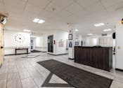 Thumbnail 8 of 13 - A reception area with a white wall and a black and white clock.