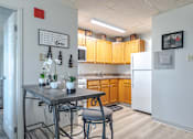 Thumbnail 3 of 13 - A kitchen with a table and chairs in front of a refrigerator.