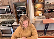Thumbnail 18 of 35 - A woman is playing a board game in a kitchen.