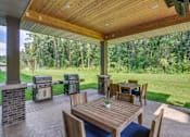 Thumbnail 6 of 35 - a covered patio with tables and barbecue grill at Arbor Ridge, Forest Lake, MN, 55025