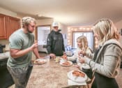 Thumbnail 30 of 32 - people gathered around a kitchen counter eating pizza at Boulder Ridge, Duluth Minnesota
