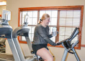 Thumbnail 21 of 31 - a woman on an exercise bike in a gym at Summit Ridge, Duluth, MN, 55811