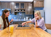 Thumbnail 38 of 67 - two girls playing chess at a kitchen table  at Timber Ridge, Forest Lake, MN, 55025