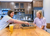 Thumbnail 40 of 67 - two women playing chess at a table in a kitchen  at Timber Ridge, Forest Lake