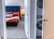 Thumbnail 28 of 67 - a bedroom with a bed and a washer and dryer in it  at Timber Ridge, Forest Lake