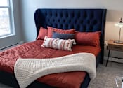Thumbnail 29 of 67 - a bedroom with a bed with red sheets and pillows  at Timber Ridge, Minnesota